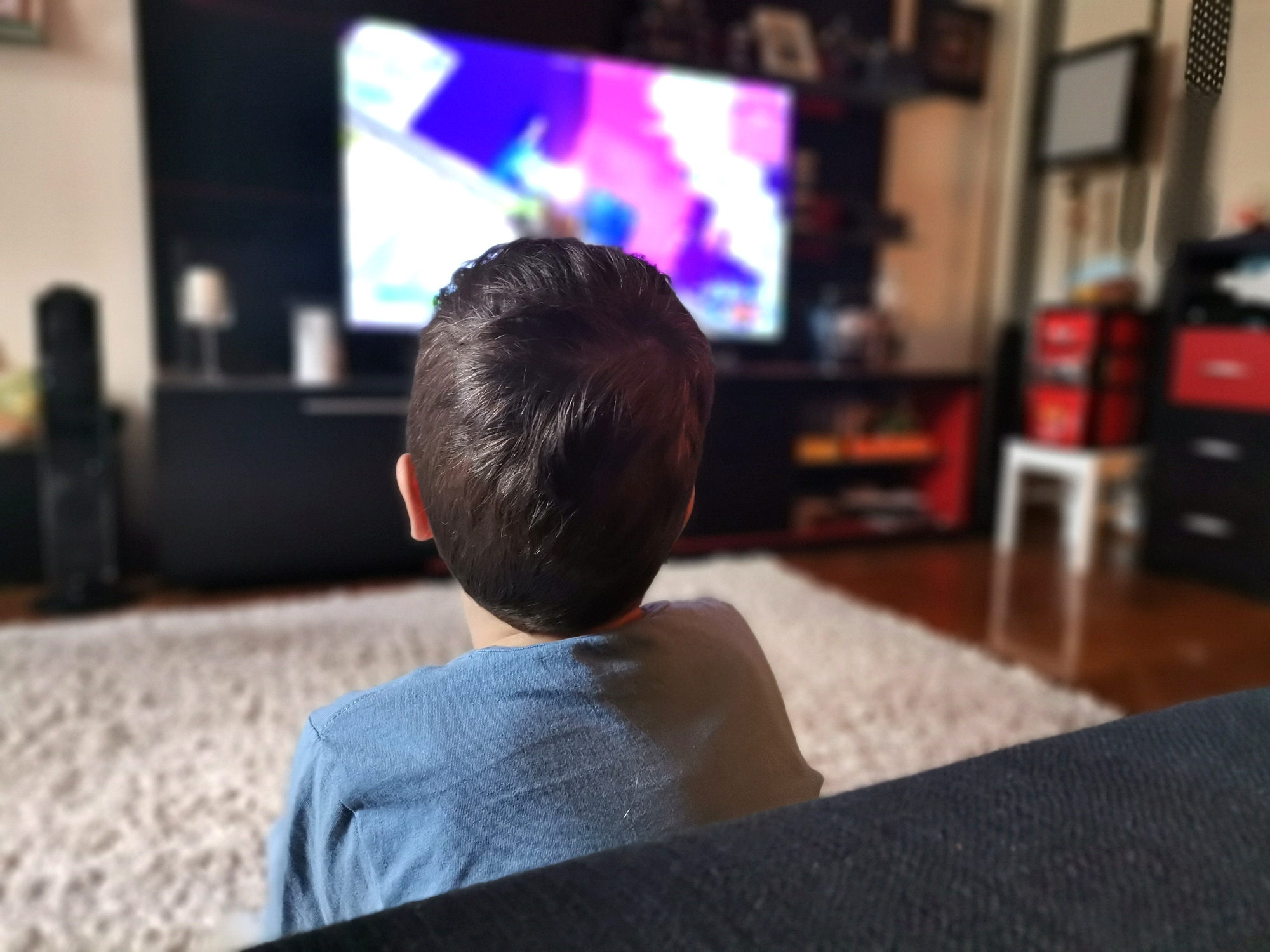 Rear view of boy watching TV at home