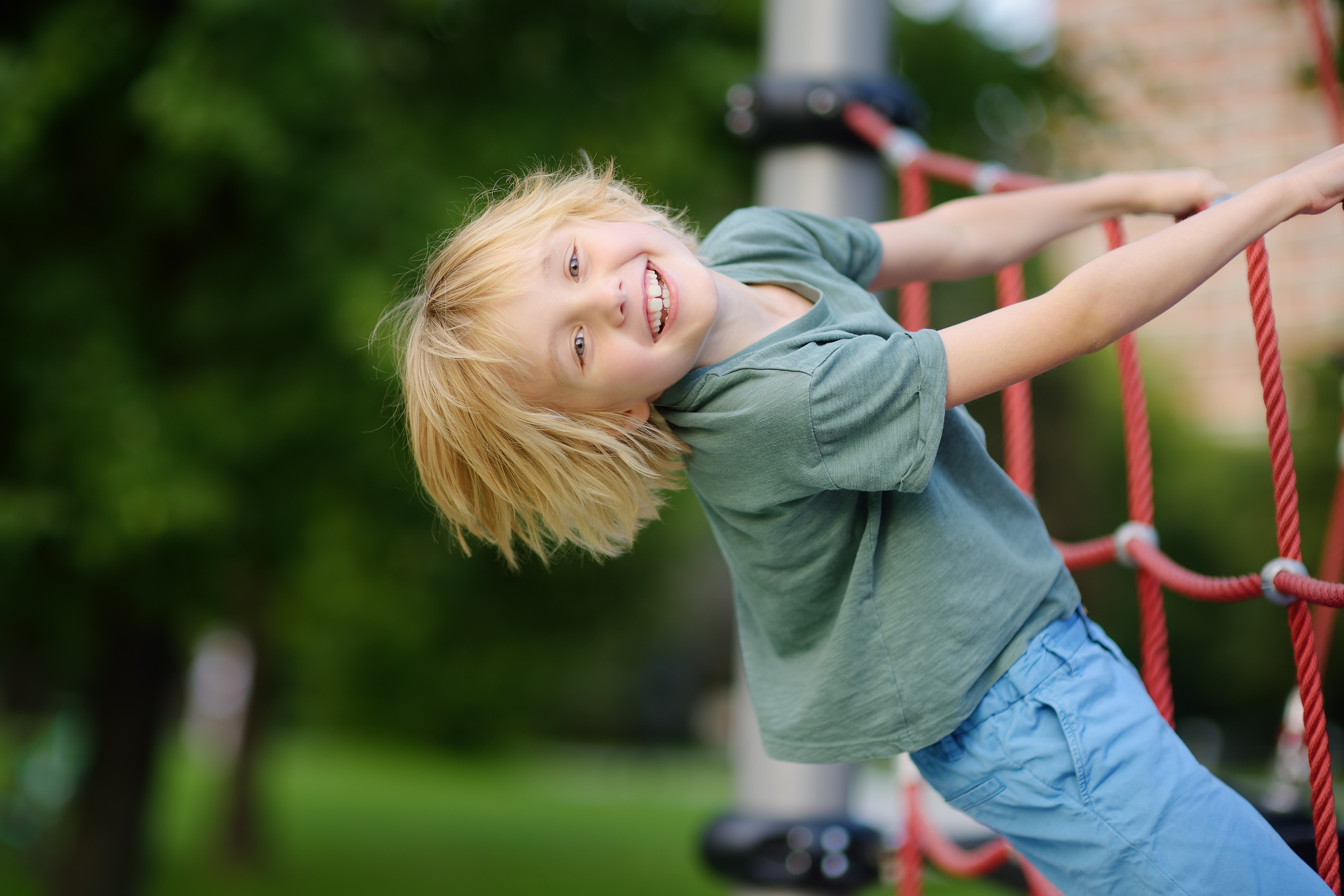 Young boy having fun on climbing net at outdoor playground