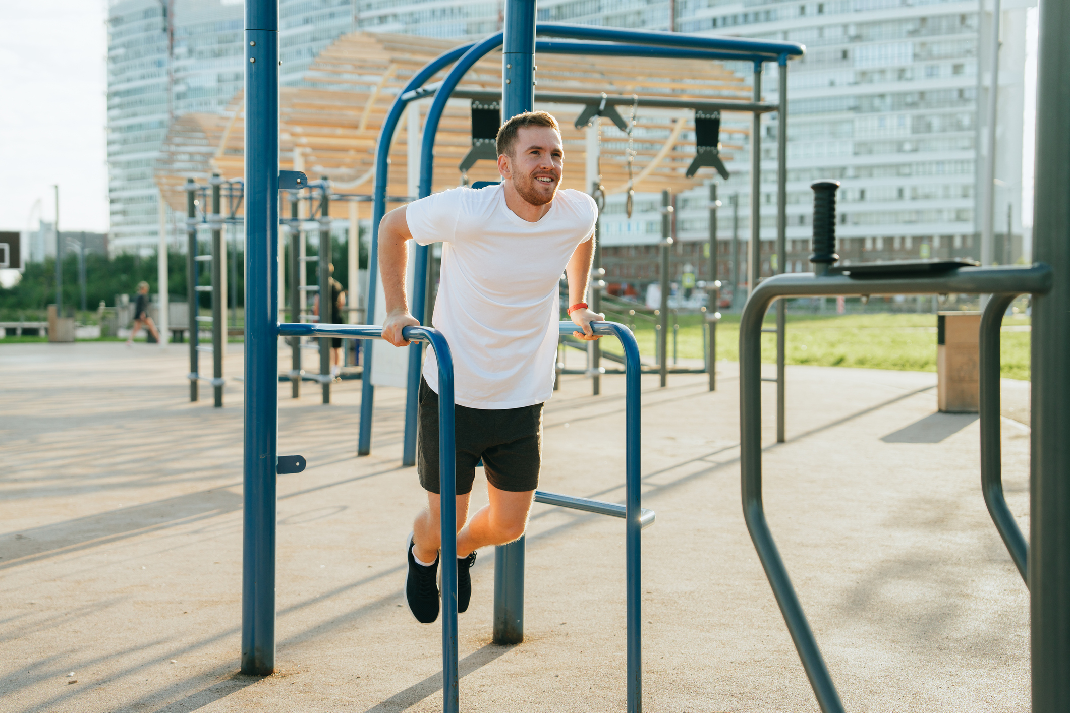 A man exercises on bars in an outdoor gym on sunny day 