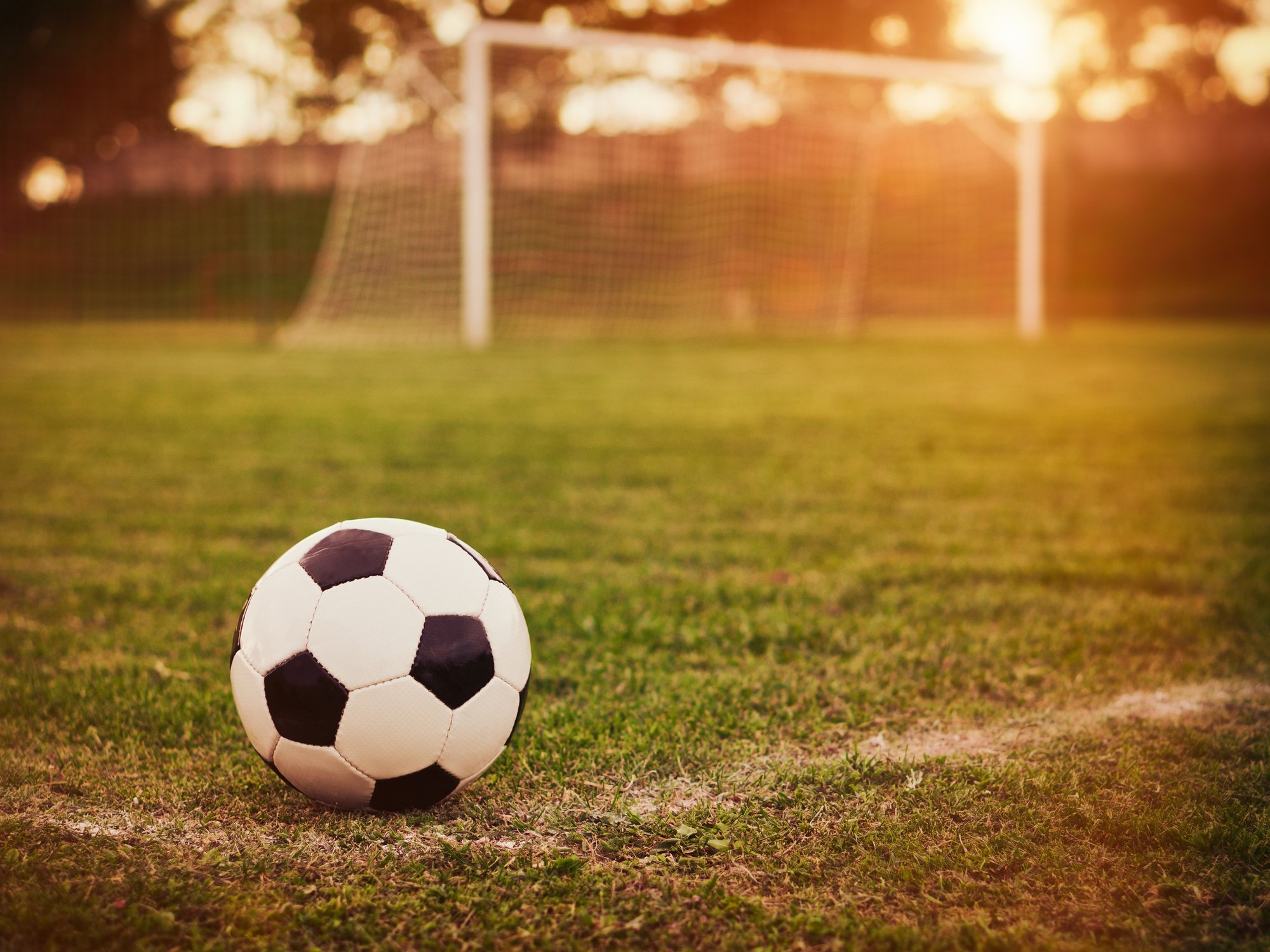 Soccer ball in front of goal during sunset